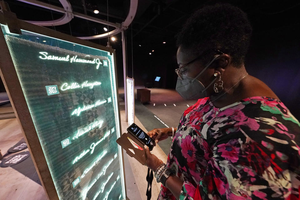 Pamela D.C. Junior, director of the Two Mississippi Museums in Jackson, searches for a specific cold case selection at the PBS Frontline's traveling augmented-reality exhibit, "Un(re)solved" in the museum's special exhibit room, Friday, Aug. 27, 2021. The exhibit was opened on Saturday, Aug. 28, to align with the commemoration of the death of Emmett Till, a Chicago teenager who was lynched in Mississippi in 1955. The multi-media platform examines the federal government's efforts to investigate more than 150 civil rights era cold cases on the Emmett Till Unsolved Civil Rights Crime Act. (AP Photo/Rogelio V. Solis)