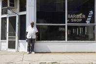 <p>A well-dressed barber stands in front of his barbershop. </p>