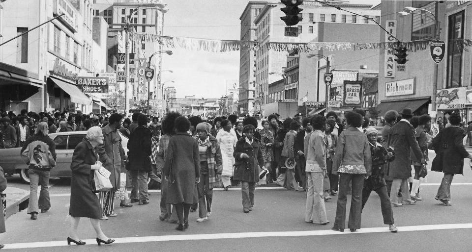 A downtown Akron shopper enters a crosswalk Oct. 17, 1972, while demonstrators gather on South Main Street.