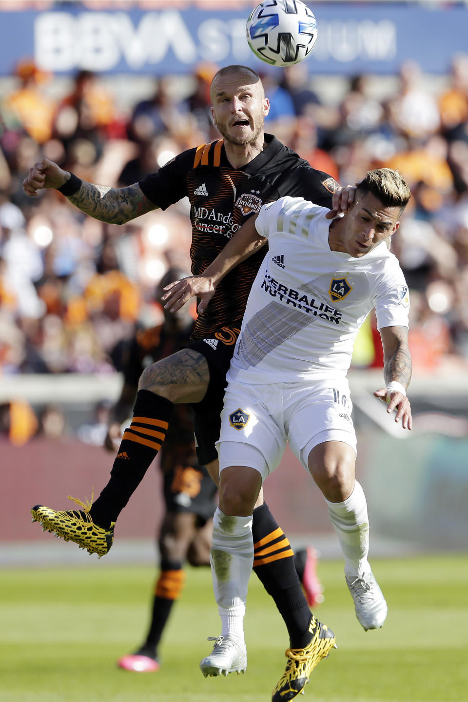 Houston Dynamo defender Kiki Struna, left, and LA Galaxy forward Cristian Pavón, right, vie for a head ball during the second half of an MLS soccer match Saturday, Feb. 29, 2020, in Houston. (AP Photo/Michael Wyke)