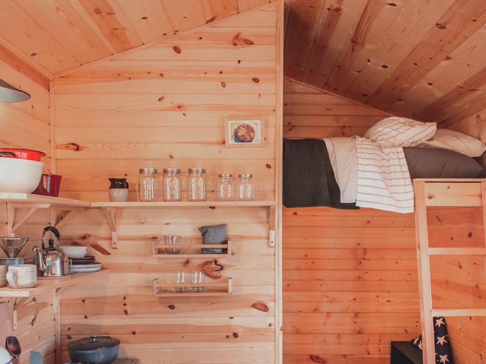 Photograph inside a tiny home with a small kitchen area and bed