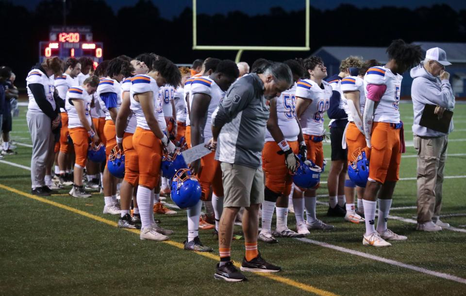 Delmar players and coaches take part in a moment of silence for teammate Carter Figgs, who lost his life in a car accident last week, before the start of Delmar's 30-27 win at Lake Forest High School, Thursday, Oct. 12, 2023.