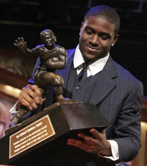 USC tailback Reggie Bush picks up the Heisman Trophy after winning the award on Dec. 10, 2005