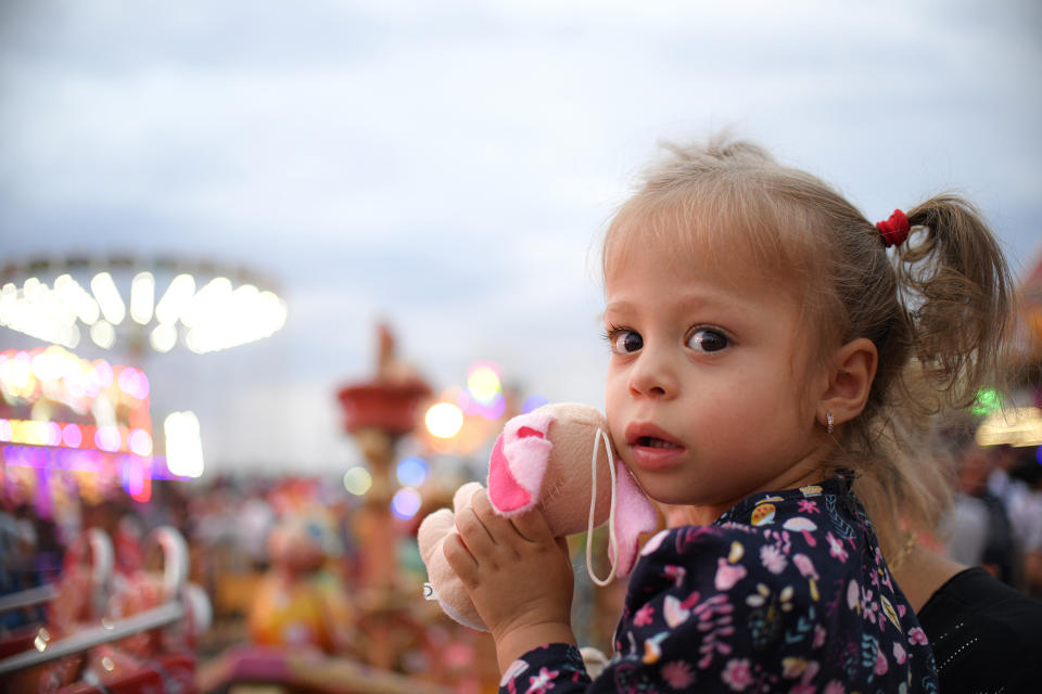 In this picture taken Saturday, Sept. 14, 2019, a little girl holds a toy at an autumn fair in Titu, southern Romania. Romania's autumn fairs are a loud and colorful reminder that summer has come to an end and, for many families in poorer areas of the country, one of the few affordable public entertainment events of the year. (AP Photo/Andreea Alexandru)