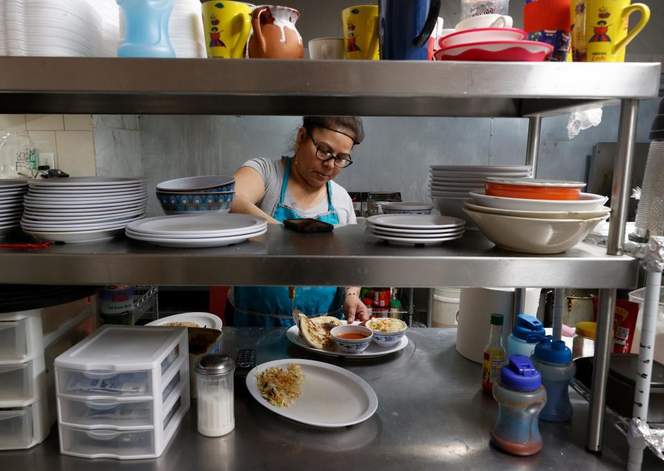 Anna Vasquez, a cook at La Cuscatleca Inc. in Detroit, adds fresh-made pupusas to an order of Salvadoran food on Feb. 24, 2022.