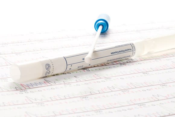 A cotton swab for a genetic test sitting on a printout of a DNA sequence.