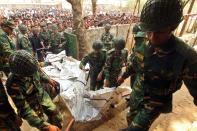 Army soldiers carry the bodies of workers were killed in a fire at a garment factory in the Savar neighborhood in Dhaka, Bangladesh, Sunday Nov. 25, 2012. At least 112 people were killed in a late Saturday night fire that raced through the multi-story garment factory just outside of Bangladesh's capital, an official said Sunday.(AP Photo/ Jibon Amir)