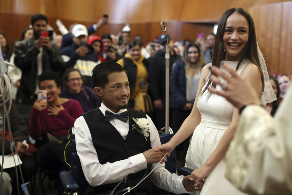 In this Wednesday, Nov. 27, 2019 photo, Javier Rodriguez and Crystal Cuevas Rodriguez and Crystal Cuevas exchange vows during their wedding before family, friends and medical staff in the chapel at the University of Chicago Medical Center for Care and Discovery in Chicago. Rodriguez, 23, who received two heart transplants as a teenager died in hospice care, days after he married his high school sweetheart, his new bride said. (Brian Cassella/Chicago Tribune via AP)