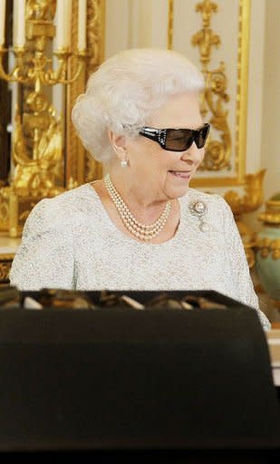 Queen Elizabeth II wears 3D glasses to watch the recording of her Christmas message to the Commonwealth which is to be broadcast in 3D for the first time, at Buckingham Palace in London on December 23, 2012. She will pay tribute to the London 2012 athletes in her annual Christmas message to the Commonwealth, saying they had inspired the world and drawn people in to the excitement and drama