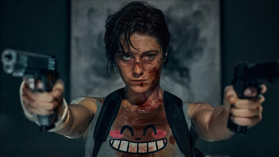 Mary Elizabeth Winstead, bloodied, holds up two guns while wearing a tanktop