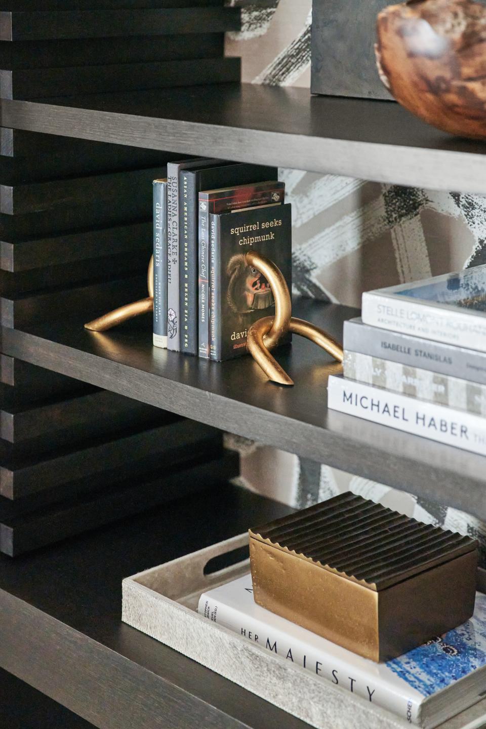 The home office in Howard’s Weatherly project features a carefully curated bookcase. Charcoal-colored books are clustered in one vignette, while light gray and white books are stacked in another.
