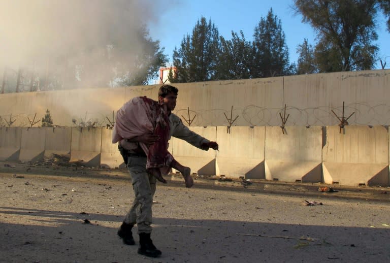 A member of the Afghan security forces carries an injured civilian after a suicide bomb attack in Lashkargah city, on November 15, 2015