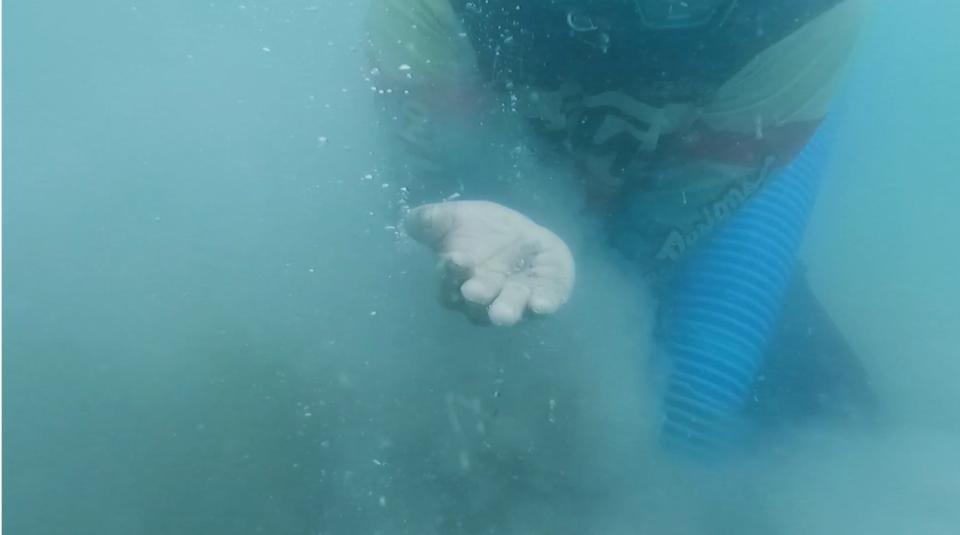 Joko holds up tin he found on the seabed