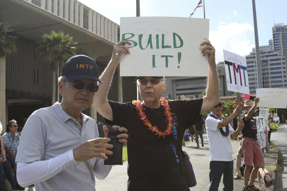 Astronomers Alan Stockton, center, holding a sign saying "Built It!," and Alan Tokunaga, left, join a rally in support the Thirty Meter Telescope outside the Hawaii State Capitol in Honolulu on Thursday, July 25, 2019. Supporters said the giant telescope planned for Hawaii's tallest mountain will enhance humanity's knowledge of the universe and bring quality, high-paying jobs, as protesters blocked construction for a second week. (AP Photo/Audrey McAvoy)