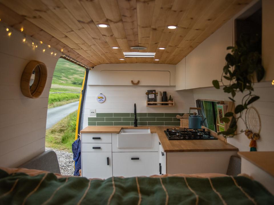 The converted van has a kitchenette on one end and a bed on the other.