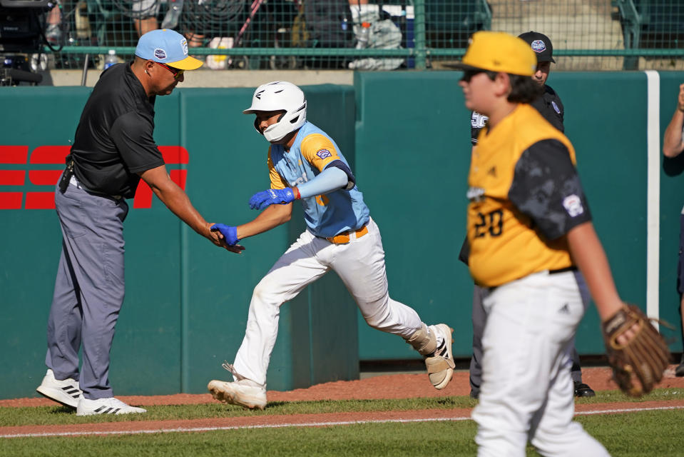 Honolulu's Rustan Hiyoto, center, rounds third to greetings from manager Gerald Oda, left, after hitting a two-run home run off Nolensville, Tenn.'s Trent McNeil (20) in the fourth inning of the United States Championship baseball game at the Little League World Series tournament in South Williamsport, Pa., Saturday, Aug. 27, 2022. (AP Photo/Gene J. Puskar)