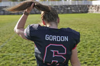 Sam Gordon adjusts her ponytail as she walks across a field, Oct. 20, 2020, in Herriman, Utah. Gordon was the only girl in a tackle football league when she started playing the game at age 9. Now, Gordon hopes she can give girls a chance to play on female-only high school teams through a lawsuit. (AP Photo/Rick Bowmer)