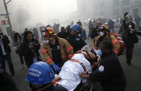 A victim is evacuated by emergency personal near an apparent building explosion fire and collapse in the Harlem section of New York City, March 12, 2014. REUTERS/Mike Segar