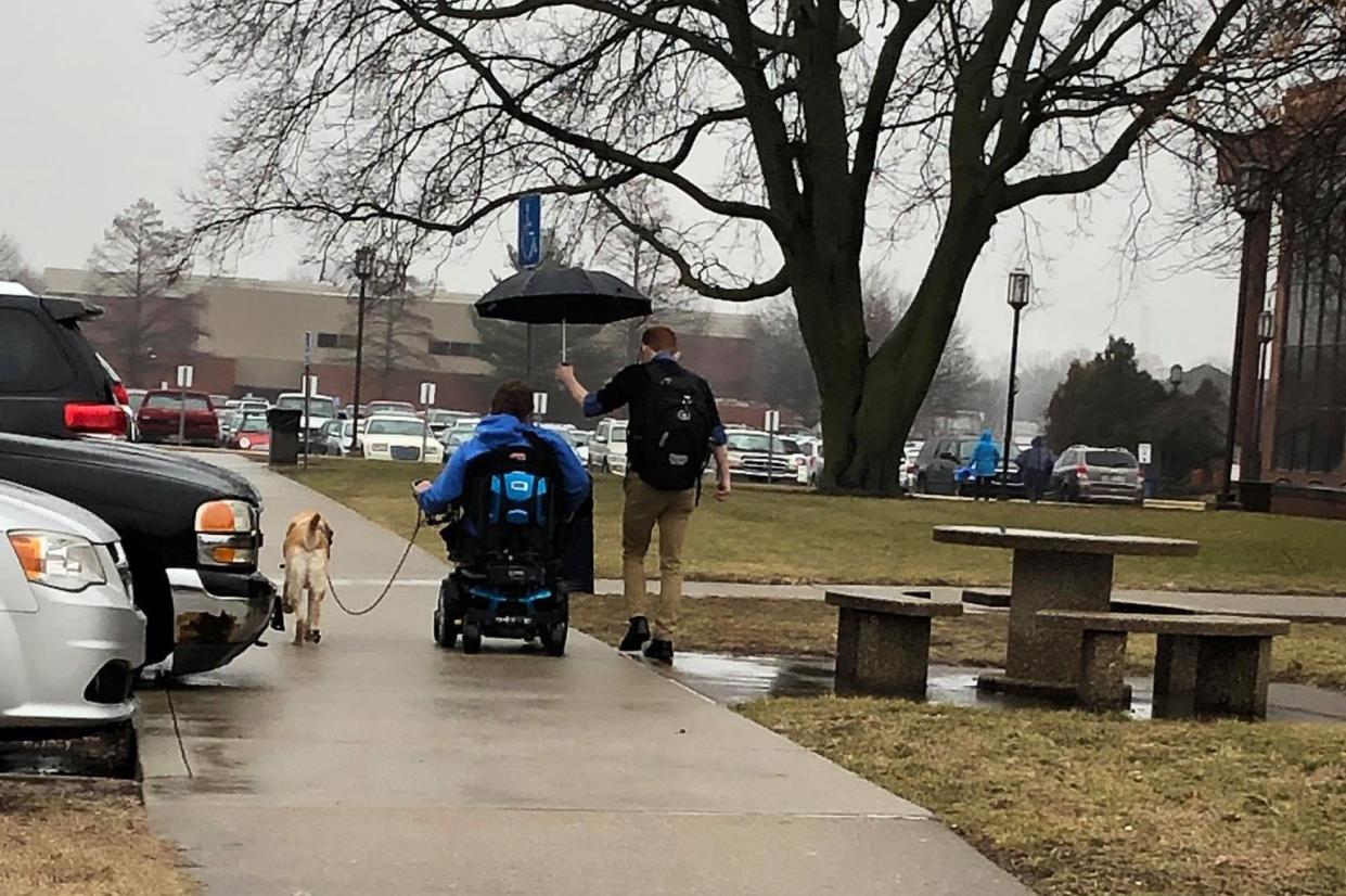 Vincennes University student Andrew Cohen ran across the parking lot to hold an umbrella for a fellow student in the pouring rain. (Credit: Elizabeth Stevens-Hardin)