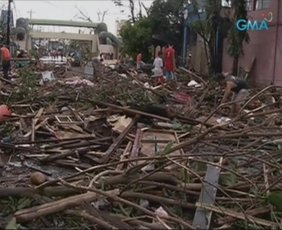 People walk on a flooded street filled with debris after Typhoon Haiyan hit the central Philippine city of Tacloban, Leyte province in this still image from video November 8, 2013. Typhoon Haiyan, possibly the strongest storm ever to hit land, has devastated Tacloban, killing at least 100 people and destroying most houses in a surge of flood water and high winds, officials said on Saturday. The toll of death and damage is expected to rise sharply as rescue workers and soldiers reach areas cut off by the massive storm, now barrelling out of the Philippines towards Vietnam. REUTERS/GMA News via Reuters TV (PHILIPPINES - Tags: DISASTER TRANSPORT ENVIRONMENT) ATTENTION EDITORS - THIS IMAGE WAS PROVIDED BY A THIRD PARTY. FOR EDITORIAL USE ONLY. NOT FOR SALE FOR MARKETING OR ADVERTISING CAMPAIGNS. NO SALES. NO ARCHIVES. THIS PICTURE IS DISTRIBUTED EXACTLY AS RECEIVED BY REUTERS, AS A SERVICE TO CLIENTS. PHILIPPINES OUT. NO COMMERCIAL OR EDITORIAL SALES IN PHILIPPINES. MANDATORY CREDIT TO GMA NEWS