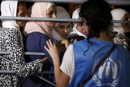 Syrian refugees listen to a United Nations High Commissioner for Refugees (UNHCR) volunteer before boarding the passenger ship "Eleftherios Venizelos" at the port on the Greek island of Kos, August 15, 2015. REUTERS/Alkis Konstantinidis
