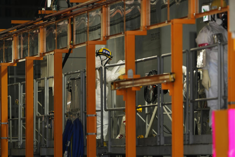 A worker looks at materials inside a building accommodating a filtering system called ALPS, as seen during a visit by The Associated Press at the Fukushima Daiichi nuclear power plant in Futaba town, northeastern Japan, Friday, July 14, 2023. The earthquake and tsunami destroyed the plant's cooling systems, causing three reactors to melt and contaminating their cooling water, which has since leaked continuously. The water is collected, treated with the filtering system and stored in some 1,000 tanks, which will reach their capacity in early 2024. (AP Photo/Hiro Komae)