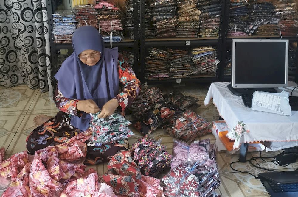 Maishom Abdullah at home sorting clothes to be sent to customers. — Picture via Twitter/AbangUdin