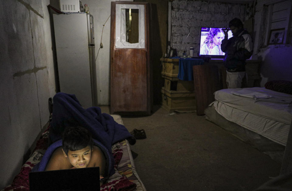 Cesar Ambrosio, son of Peruvian migrant coffin maker Carmen and Cesar Ambrosio, rests near a coffin used as furniture in his bedroom at the Bergut Funeral Services factory in Santiago, Chile, Thursday, June 18, 2020. Coffin production has had to increase up to 120%, according to Nicolas Bergerie, owner of the factory. His more basic coffin model is called the COVID model and is made to cope with the increase of deaths during the coronavirus pandemic. (AP Photo/Esteban Felix)
