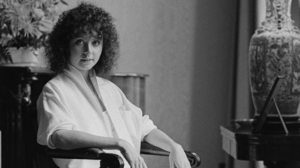 British soprano Sarah Brightman sitting in a chair, her arms on the armrests, United Kingdom, 1st April 1985.