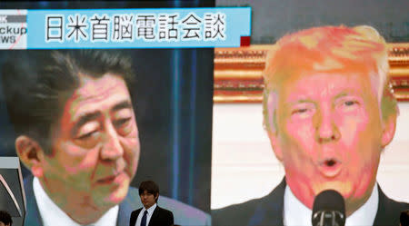 A man walks past a street monitor showing Japan's Prime Minister Shinzo Abe (L) and U.S. President Donald Trump in a news report about their telephone conference on North Korea's threat, in Tokyo, Japan, September 3, 2017. REUTERS/Toru Hanai