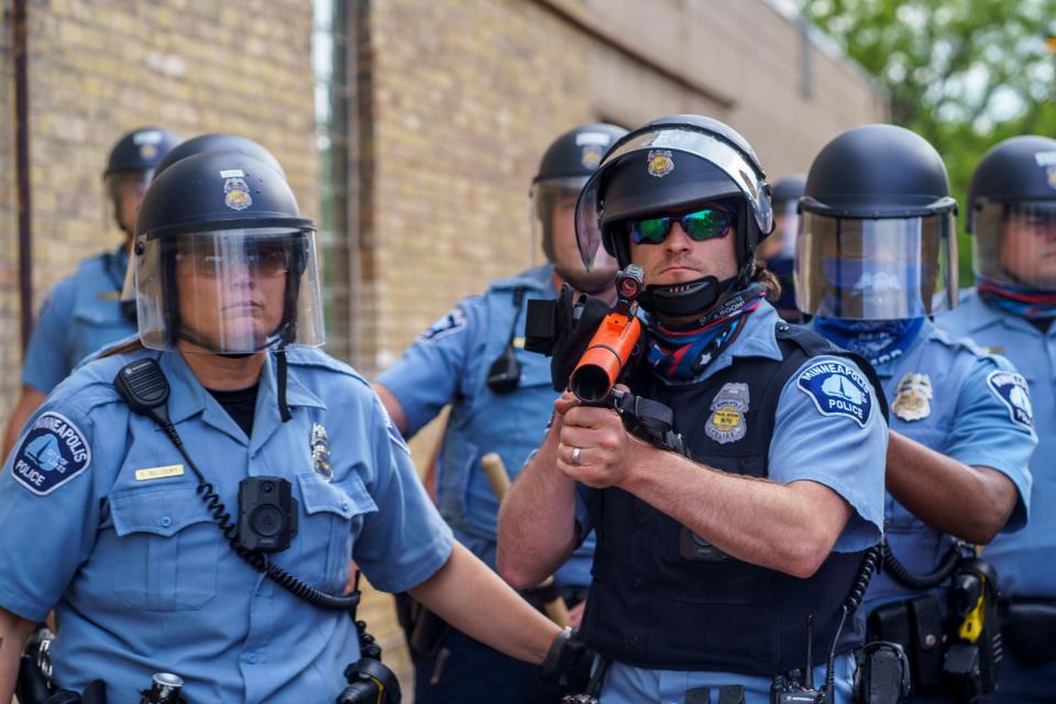 A police officer aims a projectile launcher at protesters who gathered in a call for justice for George Floyd following his death, outside the 3rd Police Precinct on May 27, 2020 in Minneapolis.
