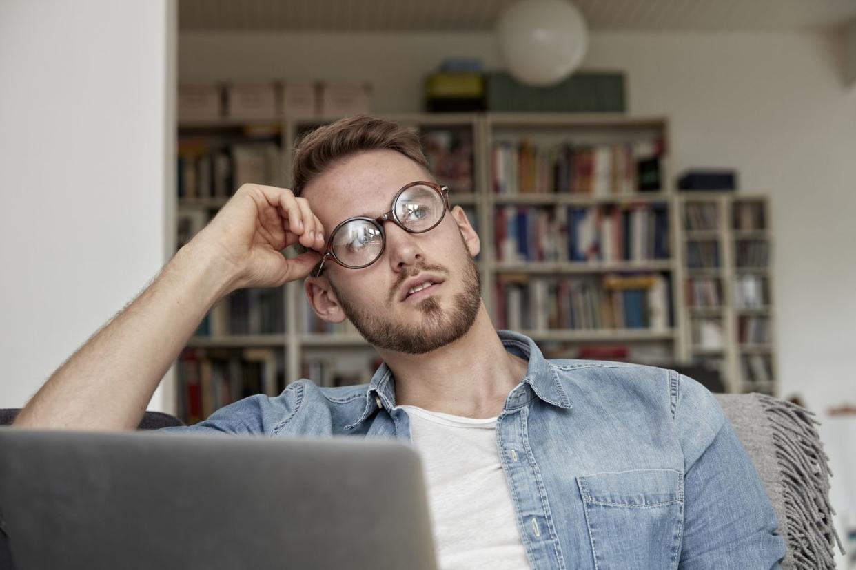 portrait of pensive man with laptop in the living room