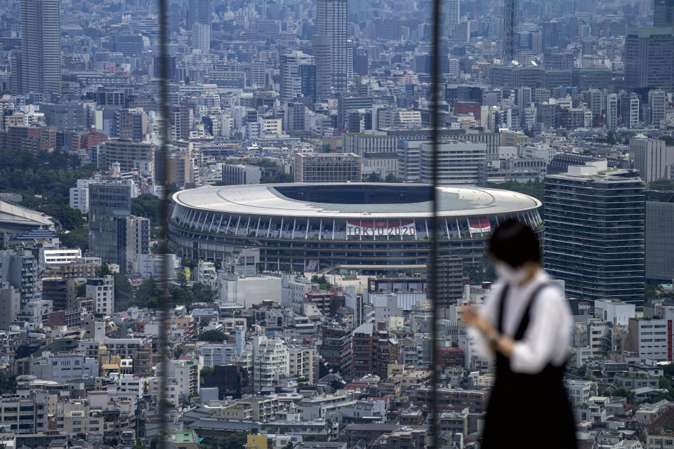 FILE - In this July 10, 2021, file photo, a person takes a picture from an observation deck as National Stadium, where the opening ceremony of the Tokyo 2020 Olympics will be held in less than two weeks is seen in the background in Tokyo. From doping, to demonstrations to dirty officials, the Olympics have never lacked their share of off-the-field scandals and controversies that keep the Games in the headlines long after the torch goes out. (AP Photo/Kiichiro Sato, File)