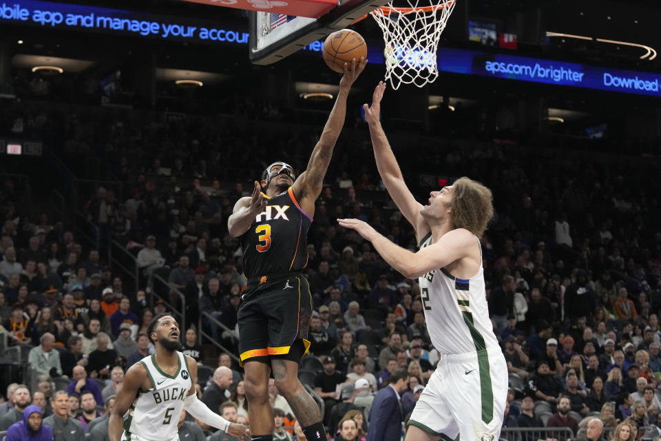 Phoenix Suns guard Bradley Beal (3) slips past Milwaukee Bucks guard Malik Beasley (5) to get a shot off against Bucks center Robin Lopez during the second half of an NBA basketball game Tuesday, Feb. 6, 2024, in Phoenix. The NBA is aiming to fetch a whopping $75 billion sports rights package. (AP Photo/Ross D. Franklin)