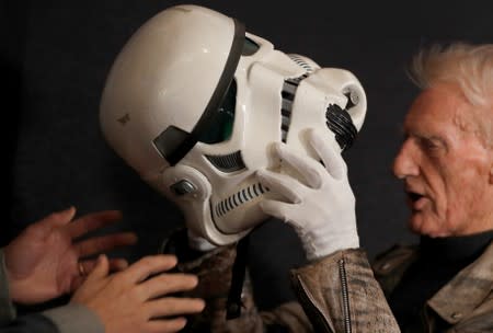 Syd Wragg, who wore this Stormtrooper helmet in the film "Star Wars: A New Hope", tries on the helmet again at a preview of a film and tv memorabilia sale in London