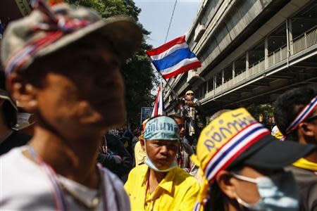 An anti-government protester waves a Thai national flag as he gathers with others during a rally at the Thai Police Headquarters in Bangkok December 18, 2013. REUTERS/Athit Perawongmetha