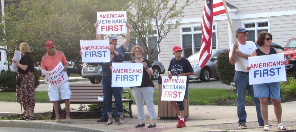 Individuals opposed to Gov. Maura Healey's plan to shelter migrants and displaced families on Cape Cod including in Bourne protested Tuesday in front of the Bourne Veterans Memorial Community Center before bringing their concerns to the Bourne Select Board at a meeting inside.