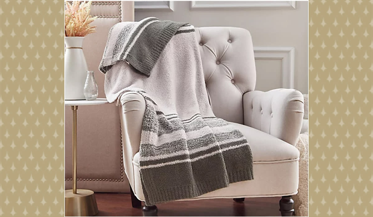 Olive and cream striped throw draped over cream upholstered chair