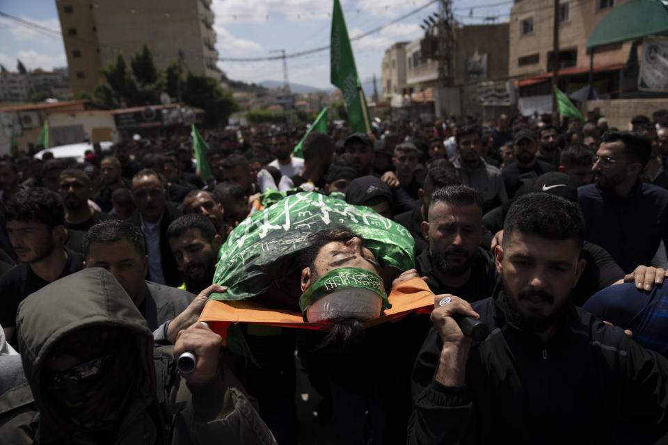 Mourners carry the body of Hamas local commander Mohammad Daraghmeh, 26, wrapped with a Hamas flag, during his funeral in the West Bank city of Tubas, Friday, April 12, 2024. Two Palestinians were killed early Friday in confrontations with Israeli forces in the Israeli-occupied West Bank, Palestinian medics and the Israeli military said. The Islamic militant group Hamas said one of those killed was a local commander. (AP Photo/Nasser Nasser)