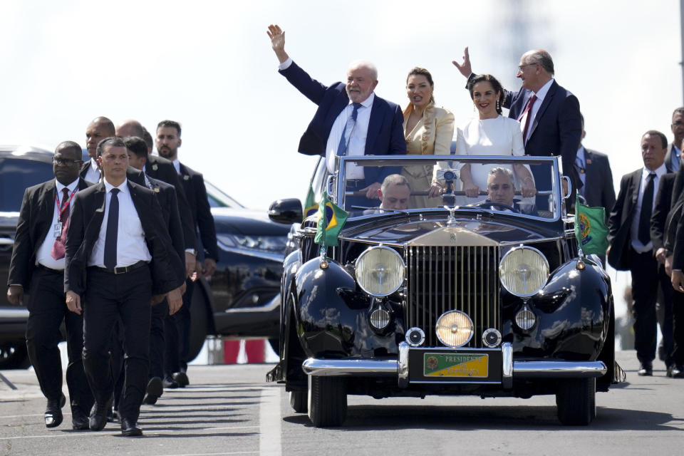 President-elect Luiz Inacio Lula da Silva, left, his wife Rosangela Silva, second from left, Vice President-elect Geraldo Alckmin, right, and his wife Maria Lucia Ribeiro, ride on an open car to Congress for their swearing-in ceremony, in Brasilia, Brazil, Sunday, Jan. 1, 2023. (AP Photo/Andre Penner)