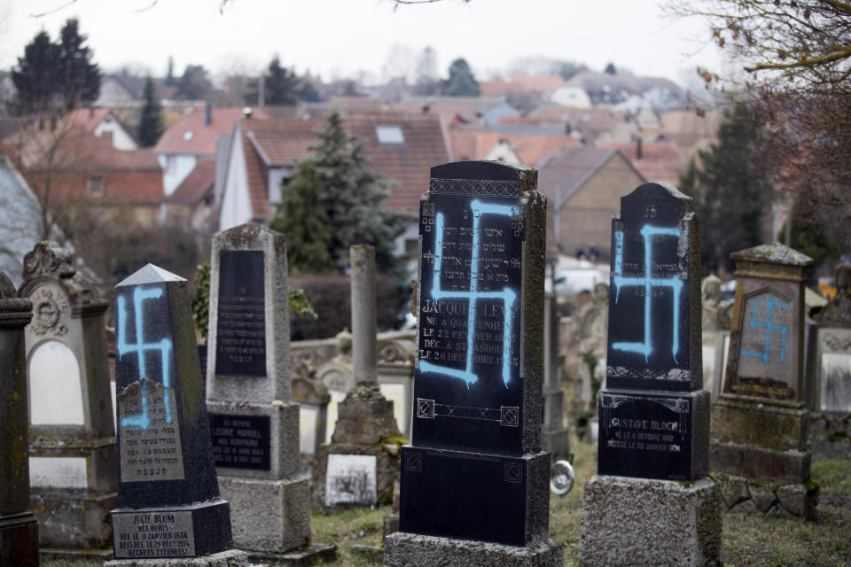 Vandalized tombs with tagged swastikas are pictured in the Jewish cemetery of Quatzenheim, eastern France, Tuesday, Feb.19, 2019. Marches and gatherings against anti-Semitism are taking place across France following a series of anti-Semitic acts that shocked the country. (AP Photo/Jean-Francois Badias)