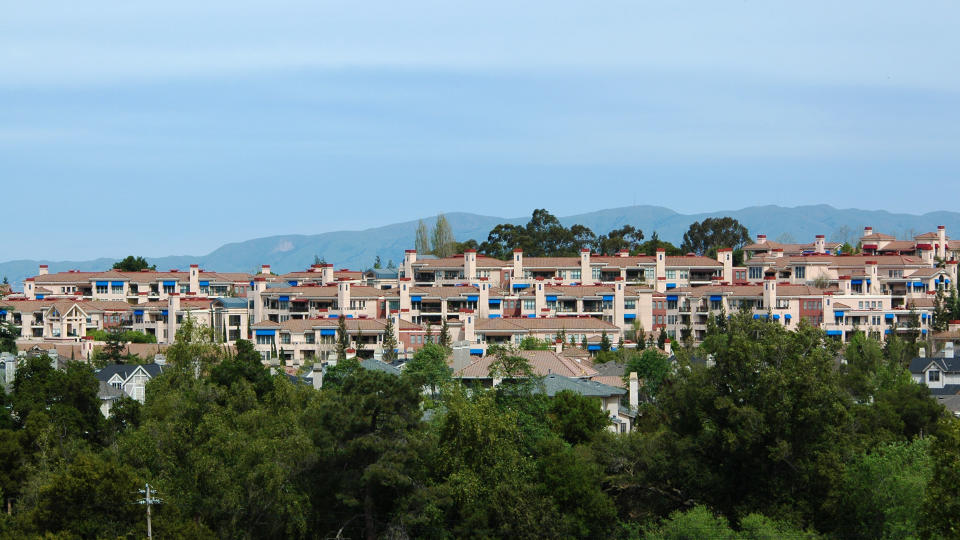 Hillside housing development sports tile roofs and blue awnings.
