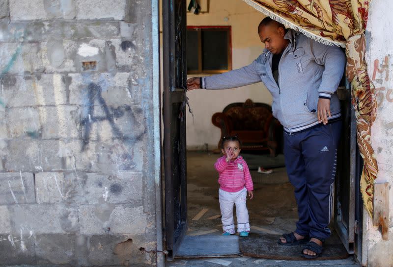 Palestinian man Eyad Al-Zahar stands next to his niece at his family home in Gaza City