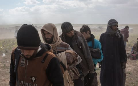 Isil members are led away to be questioned by coalition forces after surrendering, near Baghuz, eastern Syria - Credit: Sam Tarling&nbsp;