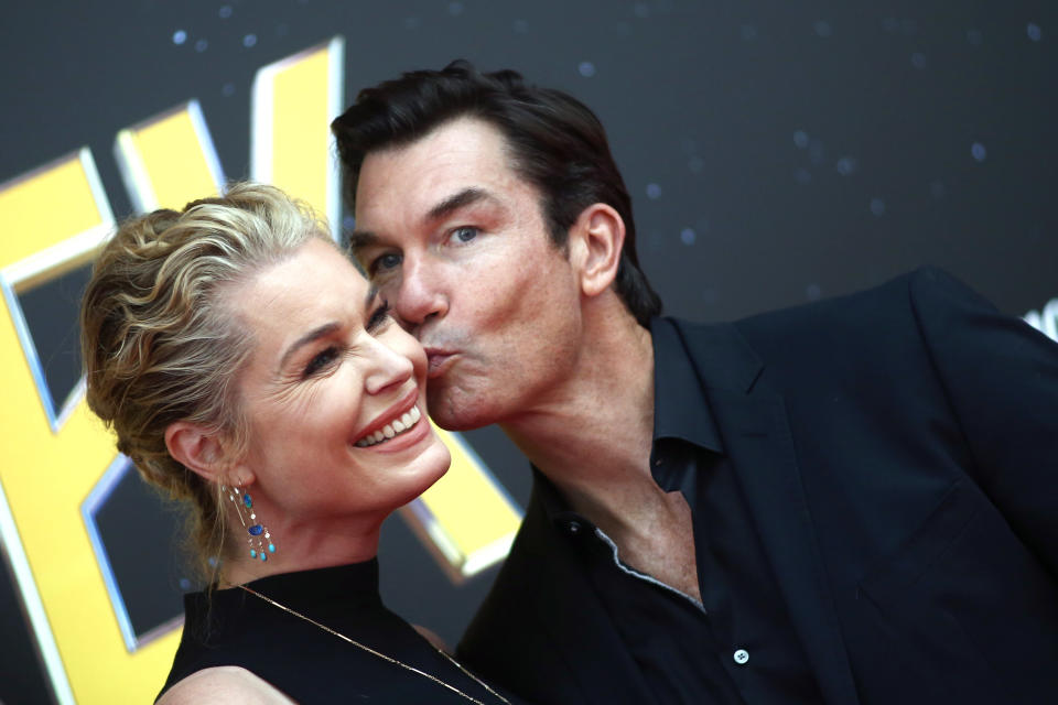 Rebecca Romijn smiles while Jerry O'Connell kisses her cheek at an event