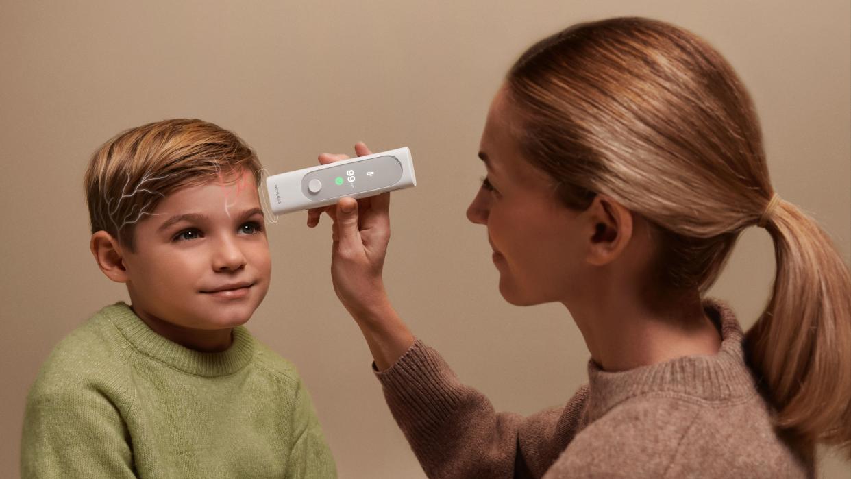  Photo showing a mother taking her son's temperature using the Withings BeamO multiscope. 