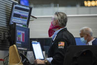 In this photo provided by the New York Stock Exchange, trader Eric Schumacher wears a bandana face mask as he works on the partially reopened trading floor, Tuesday, May 26, 2020, in New York. Stocks surged on Wall Street in afternoon trading Tuesday, driving the S&P 500 to its highest level in nearly three months, as hopes for economic recovery overshadow worries about the coronavirus pandemic. (Colin Zimmer/New York Stock Exchange via AP)