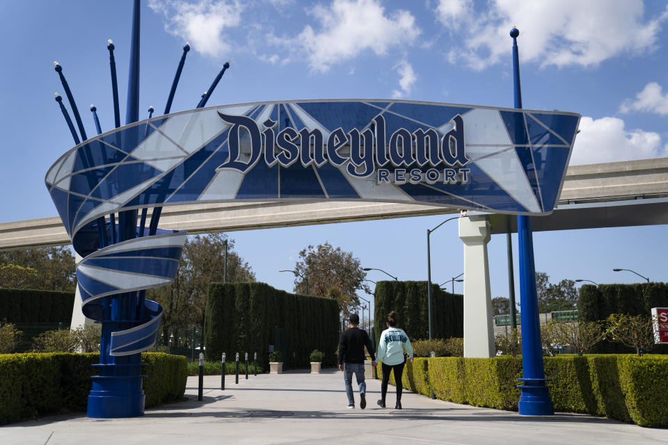 FILE - Two visitors enter Disneyland Resort in Anaheim, Calif., March 9, 2021. Disney is seeking approval from local officials to expand its California theme park offerings over the next four decades. The proposal wouldn't increase the company's geographic footprint in Anaheim, Calif., but would allow for new attractions, for example, on what is currently a large parking lot. (AP Photo/Jae C. Hong, File)