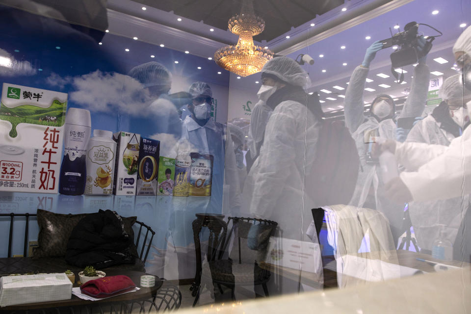 In this Thursday, Feb. 27, 2020, photo, journalist are reflected on the glass of a room near a board showing the products of the Mengniu dairy factory in Beijing. Reporters were invited to China Mengniu Dairy Co. Ltd. this week to be shown how companies are reviving after anti-virus measures shut down most of the world's second-biggest economy. (AP Photo/Ng Han Guan)