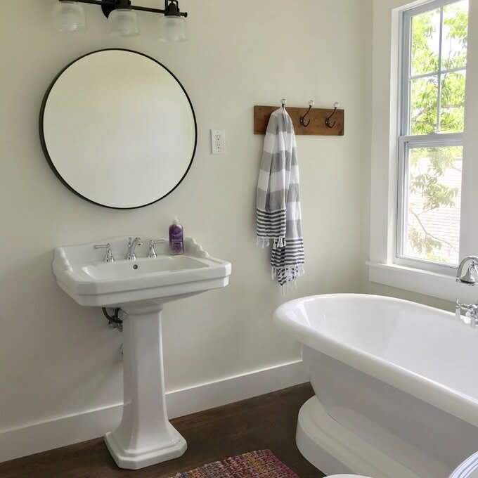 a reviewer's black circular mirror hung above a bathroom faucet